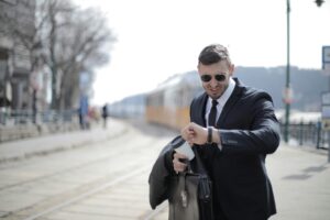 A businessman in a suit checks his watch while rushing on a sunny day in the city.